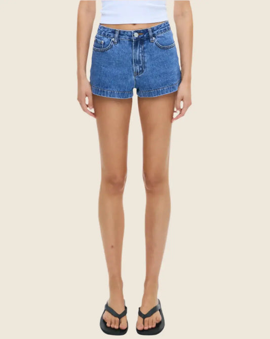 Person wearing blue denim shorts on a beige background