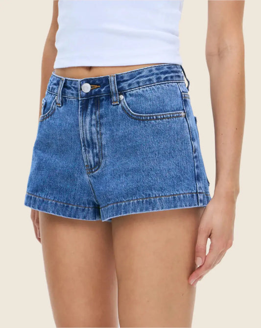 Person wearing blue denim shorts on a beige background