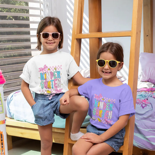 Two children wearing sunglasses and colorful t-shirts sitting on a wooden ladder.