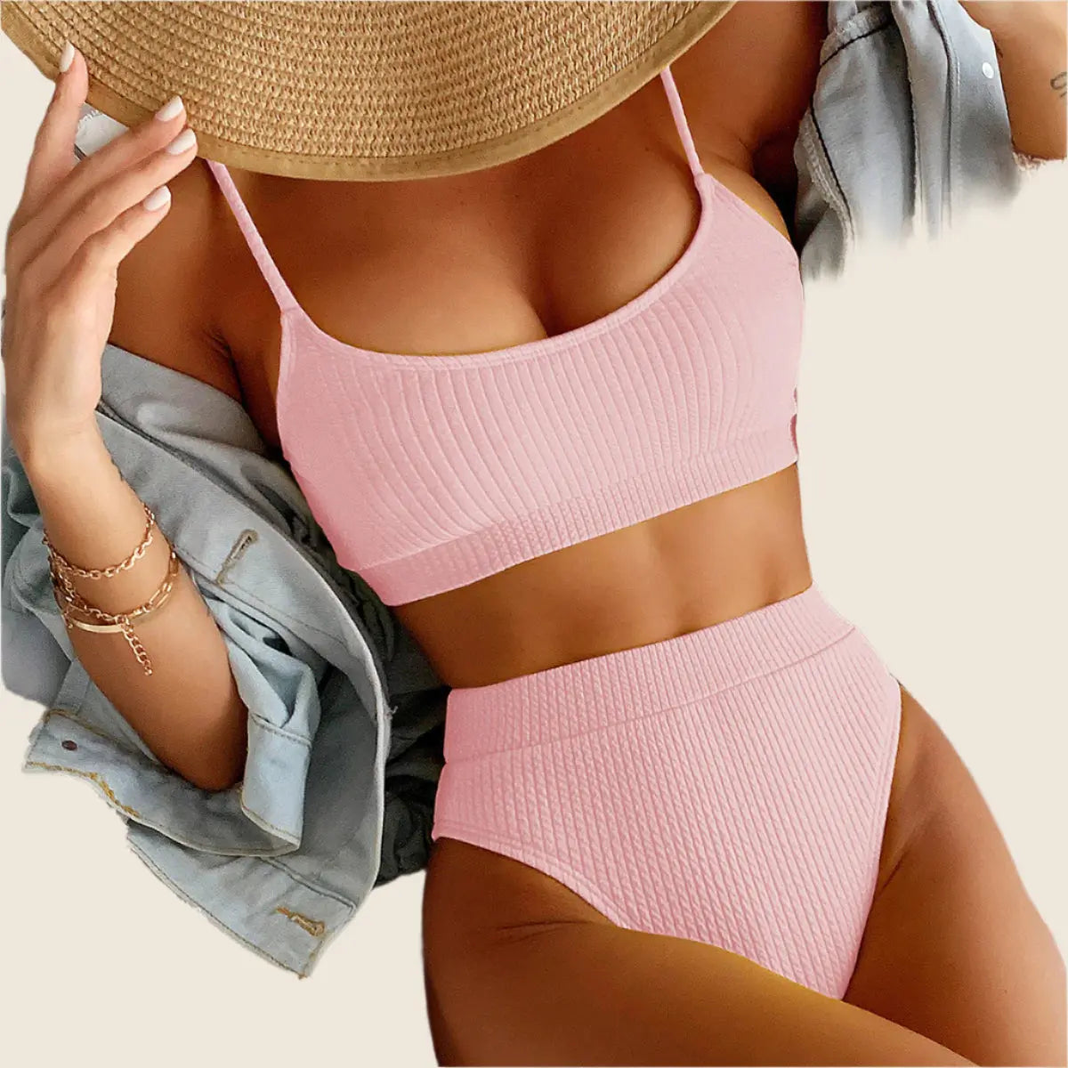 Person wearing a pink bikini and straw hat on a neutral background