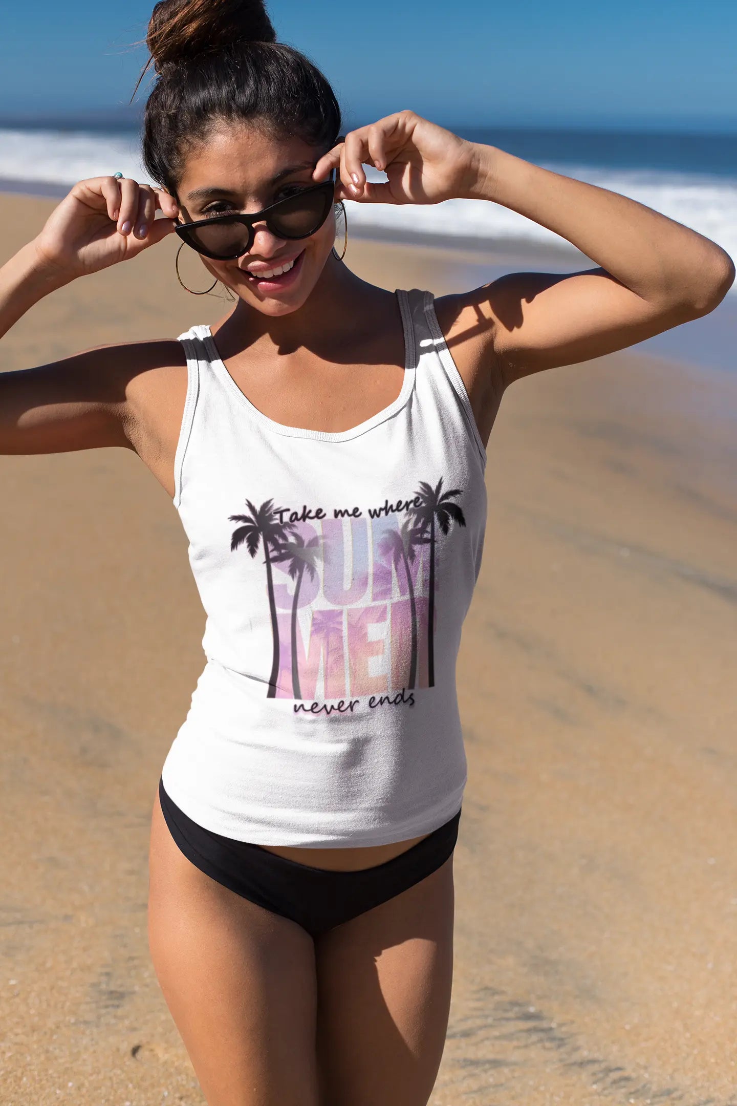 Woman wearing a white tank top with palm tree design and 'Take me where Summer never ends' text on a beach.