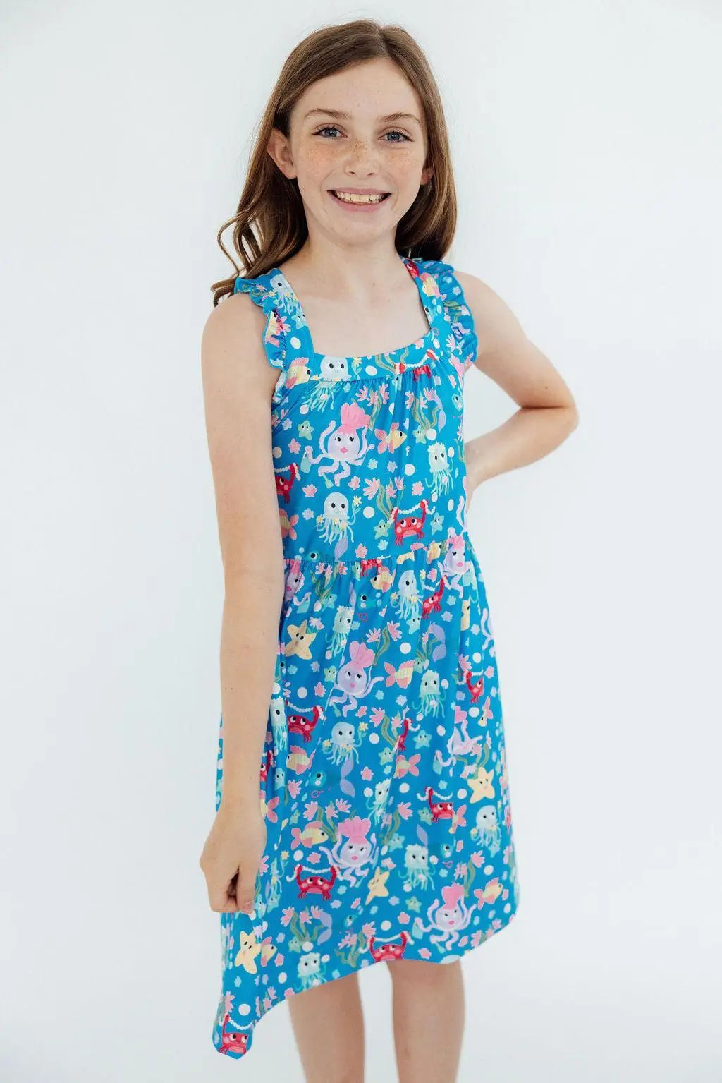 Girl wearing a blue dress with cartoon character print on a white background