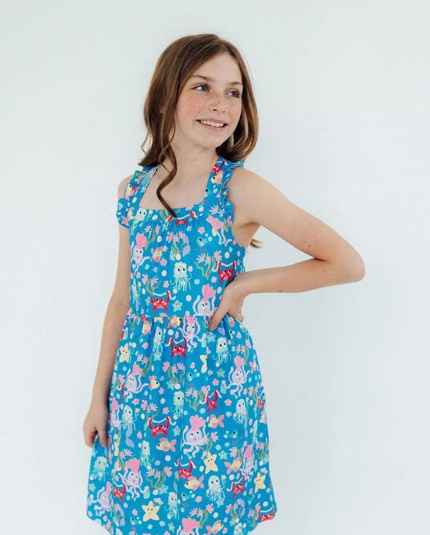 Young girl wearing a blue jellyfish summer dress on a white background