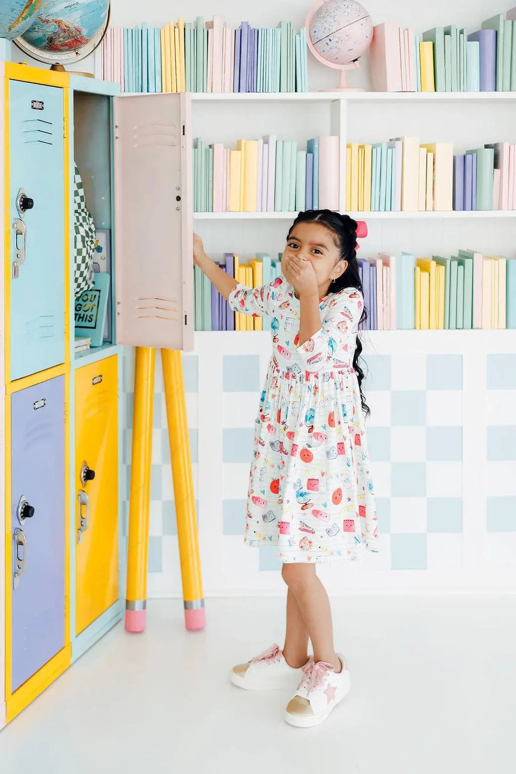 Child in a colorful room with lockers and shelves filled with books