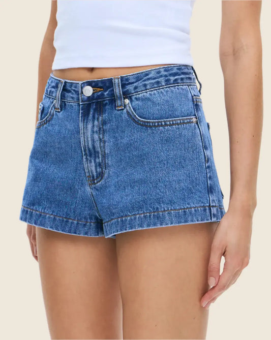 Blue denim shorts worn by a person on a beige background