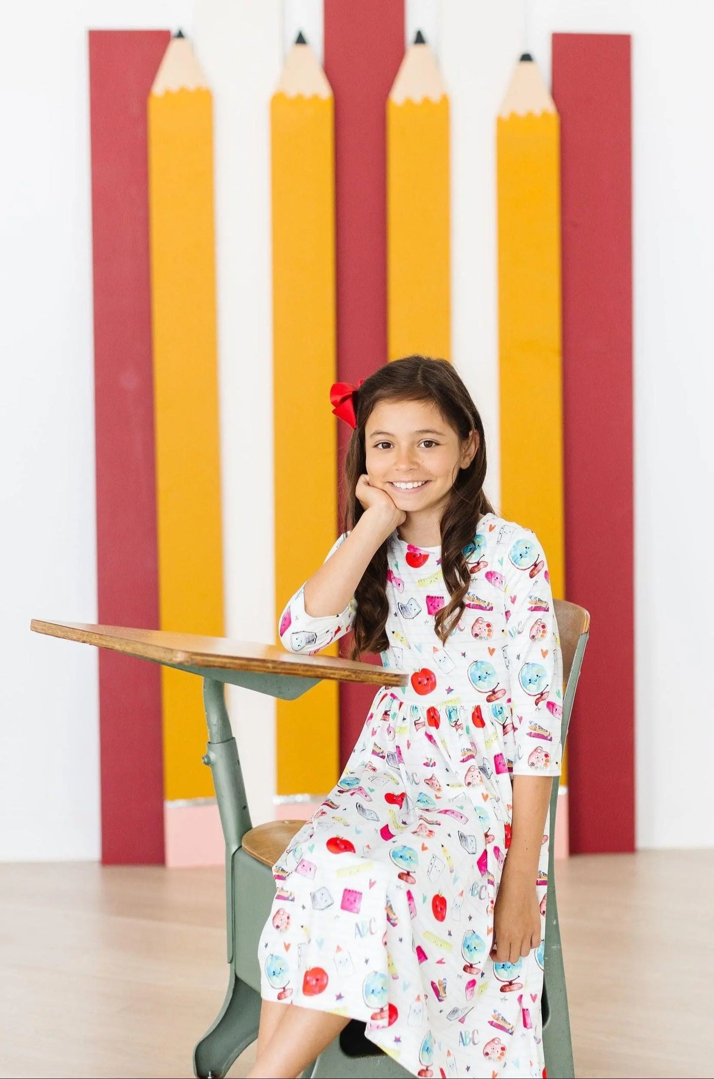 Young girl sitting at a desk  wearing a colorful dress with educational patterns