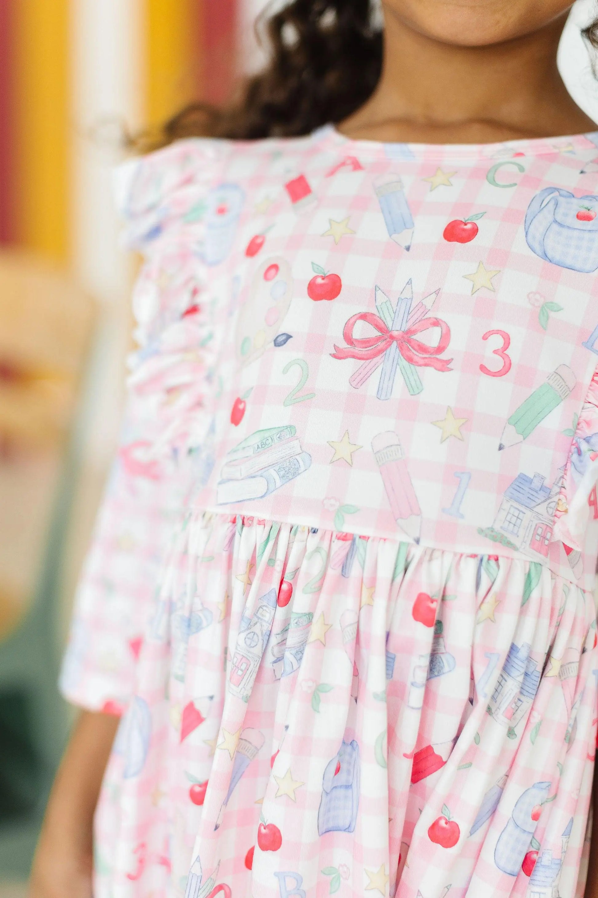 Child wearing a pink dress with colorful patterns and numbers