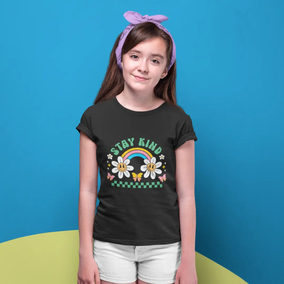 Young girl wearing a black t-shirt with a rainbow design and the text stay kind 