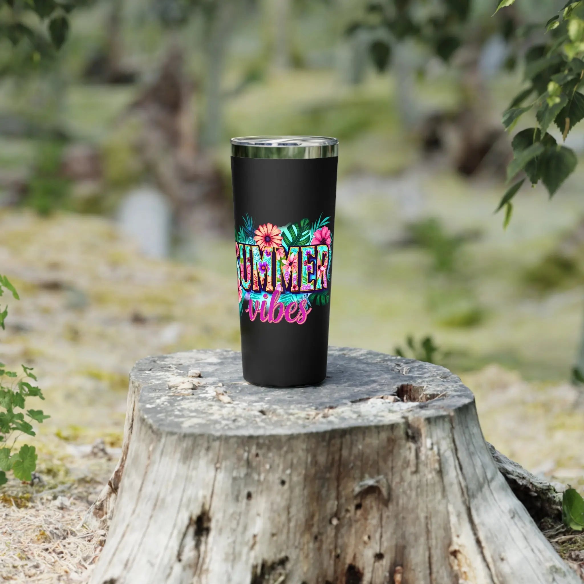 Black tumbler with 'Summer vibes' design on a wooden stump outdoors