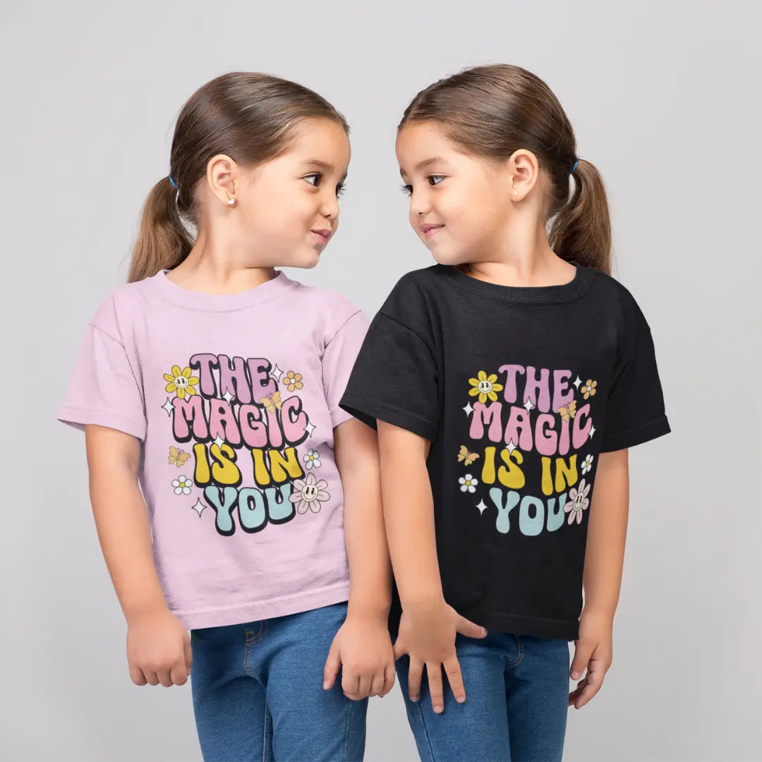 Two children wearing t-shirts with 'The Magic is in You' text on a gray background