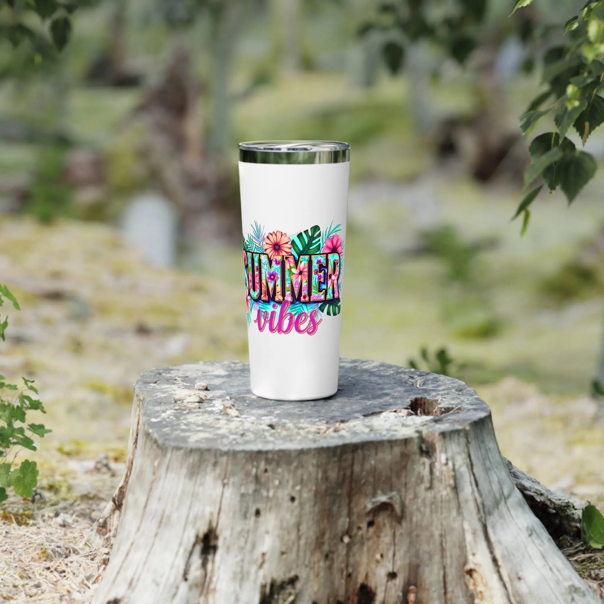 White tumbler with 'Summer vibes' text and floral designs on a wooden stump with a natural background