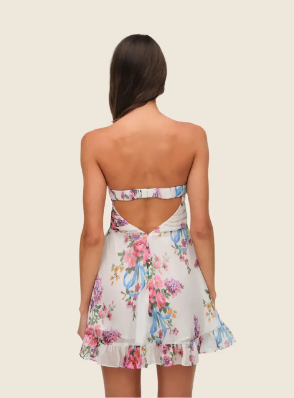 Woman wearing a floral dress with a backless design on a beige background