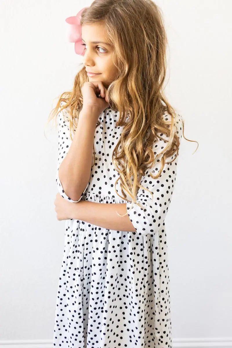 Young girl wearing a polka dot dress against a white background