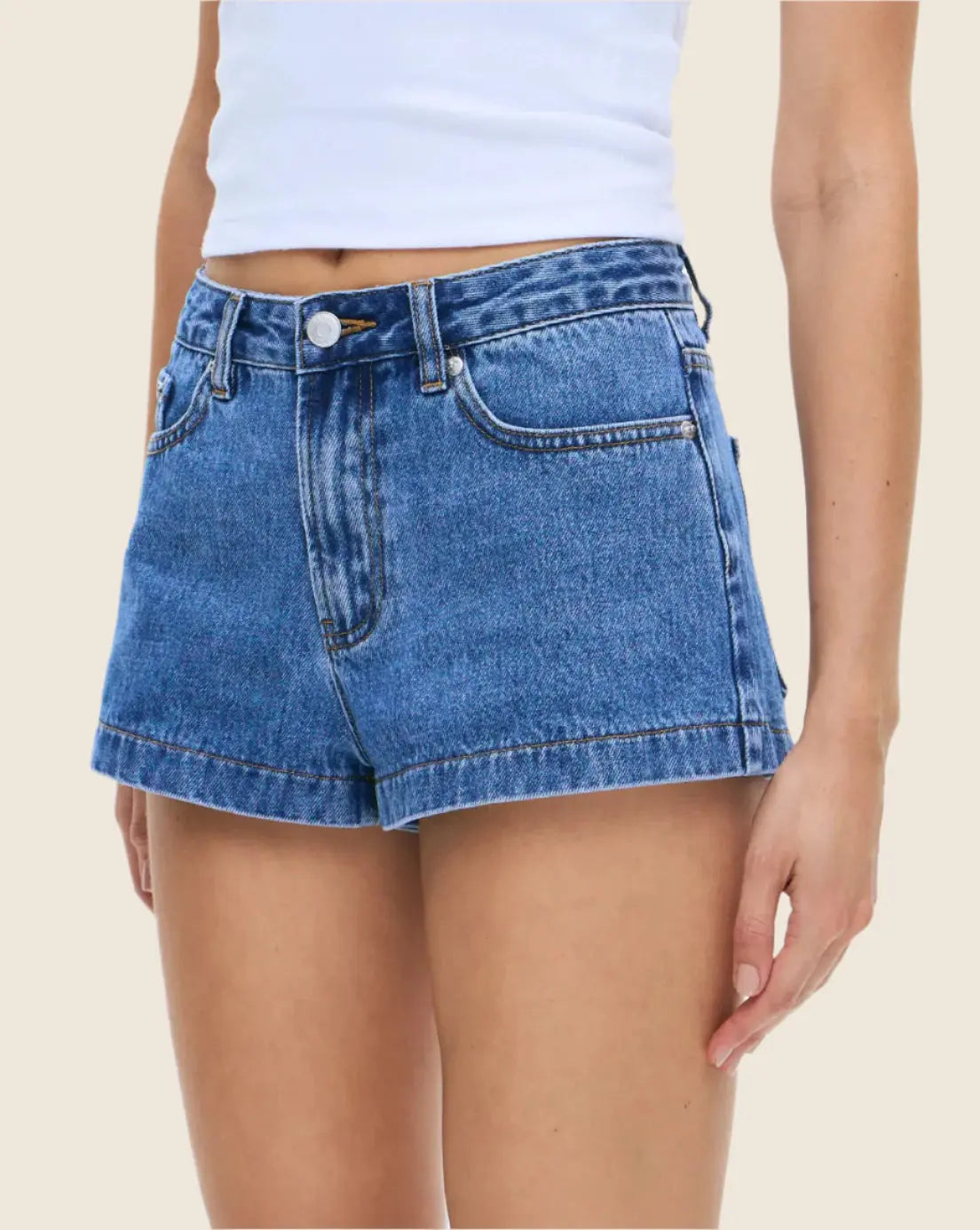 Person wearing blue denim shorts on a beige background