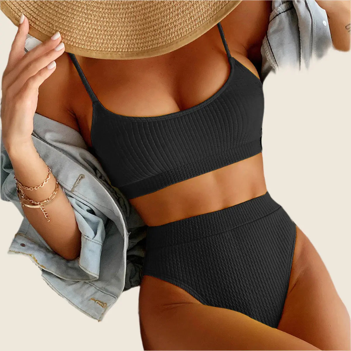 Person wearing a black ribbed bikini set with a beige background