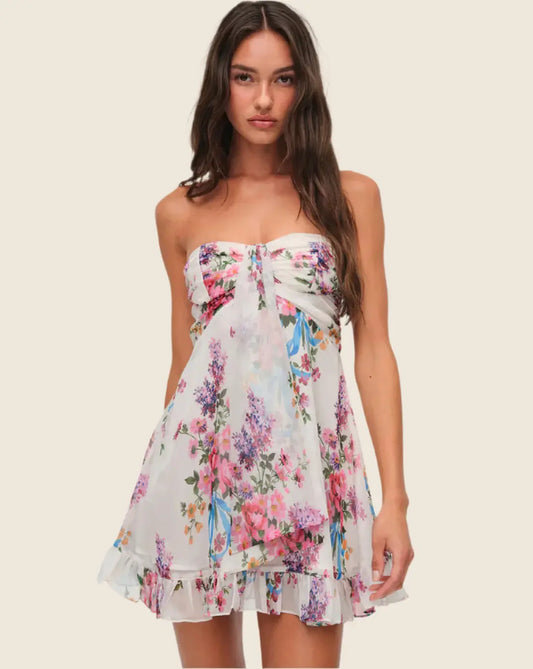 Woman wearing a floral strapless dress on a plain background