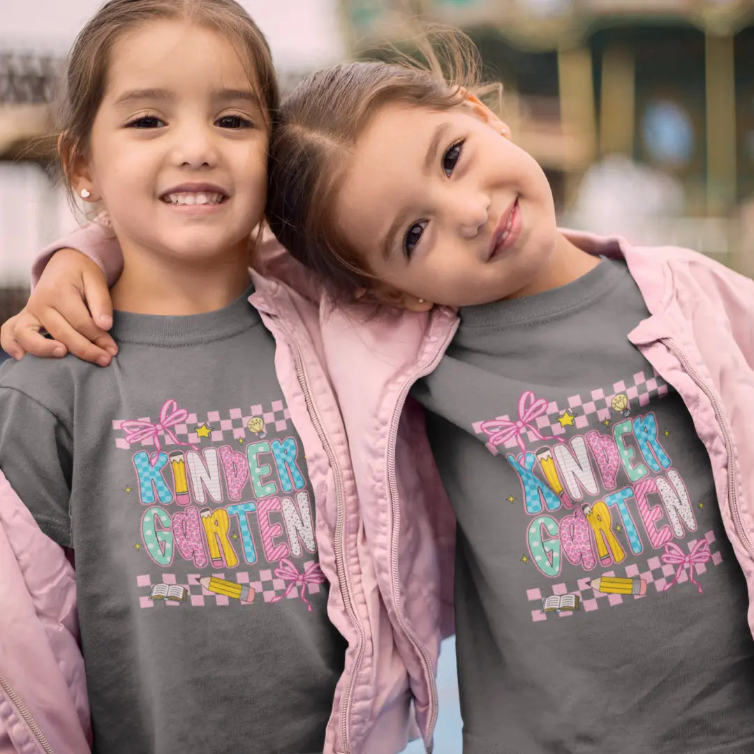 Two children wearing matching shirts with 'Kindergarten' text, standing close together.