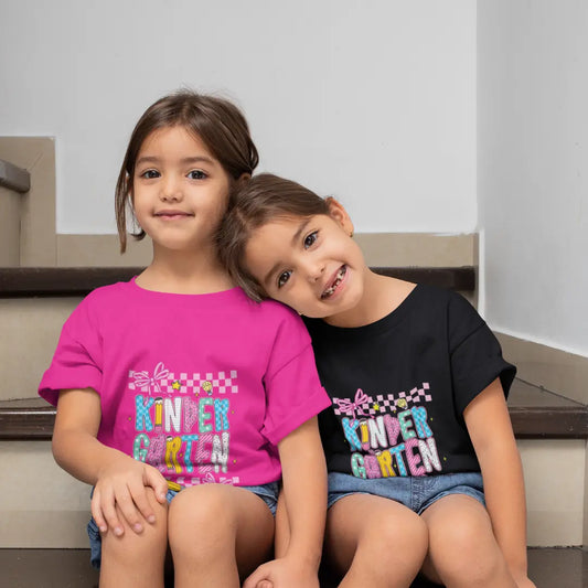 Two young girls wearing 'Kindergarten' t-shirts sitting on stairs.