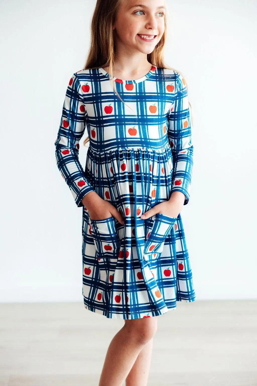 Girl wearing a blue plaid dress with red and orange accents on a white background