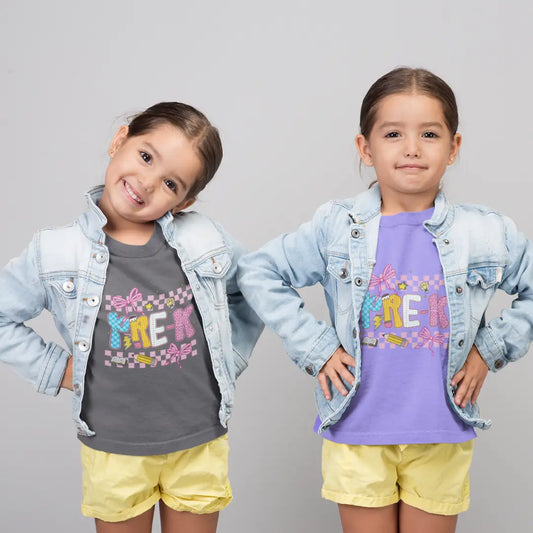 Two young girls wearing denim jackets and colorful t-shirts on a gray background
