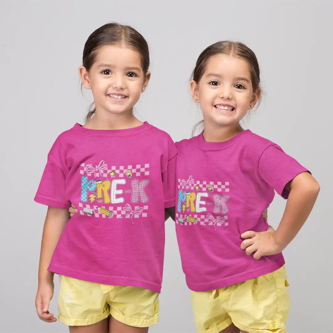Two children wearing matching pink t-shirts with colorful text and yellow shorts on a gray background.