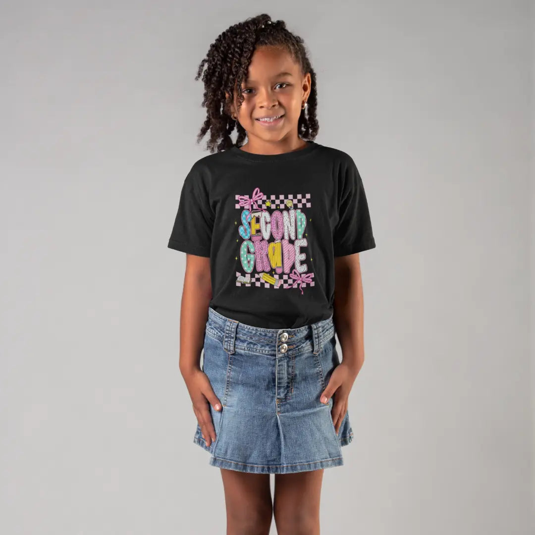 Young girl wearing a black t-shirt with 'Second Grade' text and a denim skirt on a gray background